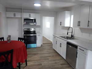 Kitchen featuring white cabinets, sink, appliances with stainless steel finishes, and light hardwood / wood-style flooring