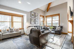 Living room with vaulted ceiling with beams, a healthy amount of sunlight, and baseboard heating