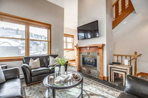 Living room with a tile fireplace, a high ceiling, and a baseboard radiator