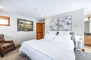 Bedroom with sink, light hardwood / wood-style flooring, a baseboard radiator, and ensuite bath