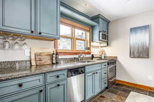 Kitchen with blue cabinets, sink, and appliances with stainless steel finishes