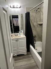 Bathroom with hardwood / wood-style flooring, vanity, and shower / tub combo with curtain