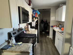 Kitchen featuring white cabinets, sink, stainless steel appliances, and dark wood-type flooring