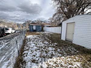 Snowy yard featuring a mountain view and a storage shed