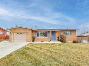 Ranch-style home featuring a front lawn and a garage