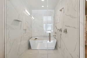 Bathroom featuring separate shower and tub and tile walls