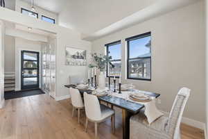 Dining space with plenty of natural light, light wood-type flooring, and a towering ceiling