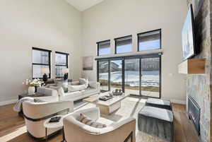 Living room with a towering ceiling, light hardwood / wood-style floors, and a stone fireplace