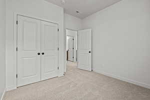 Unfurnished bedroom featuring light carpet and a closet