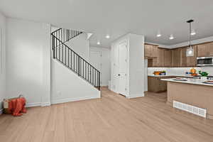 Kitchen featuring backsplash, decorative light fixtures, and light hardwood / wood-style flooring