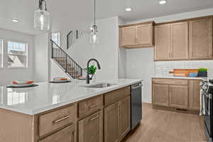 Kitchen featuring stainless steel dishwasher, range, sink, and hanging light fixtures