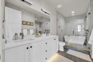 Full bathroom with tile patterned flooring, vanity, separate shower and tub, and toilet