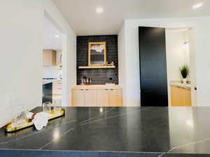 Bar featuring light brown cabinets and tasteful backsplash