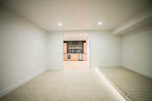 Unfurnished room with sink, light carpet, and beverage cooler