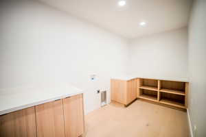 Laundry area with hookup for an electric dryer, hookup for a washing machine, and light hardwood / wood-style floors