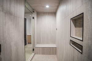 Bathroom featuring tile patterned flooring, a shower, and tile walls