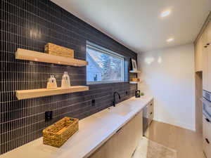 Kitchen with dishwasher, light wood-type flooring, tile walls, and sink