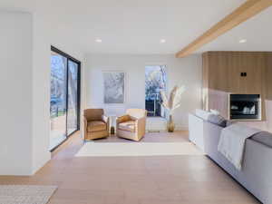 Living area with beam ceiling, a fireplace, and light hardwood / wood-style flooring