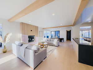 Living room featuring beam ceiling, a large fireplace, and light hardwood / wood-style flooring