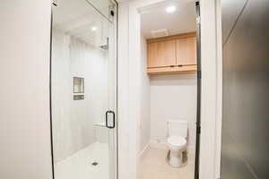 Bathroom featuring a shower with shower door and toilet