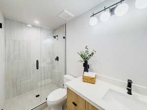 Bathroom with an enclosed shower, vanity, and toilet