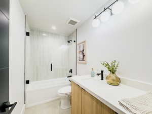 Full bathroom featuring vanity, tiled shower / bath combo, and toilet