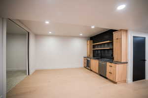 Kitchen featuring light brown cabinets, sink, stainless steel dishwasher, decorative backsplash, and beverage cooler