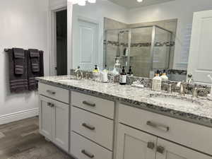 Bathroom with vanity, wood-type flooring, and a shower with door