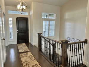 Entryway with dark wood-type flooring and an inviting chandelier