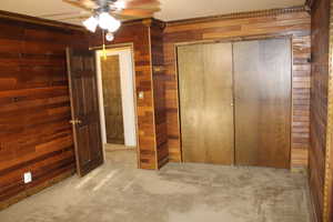 Unfurnished bedroom with wood walls, light carpet, and a textured ceiling