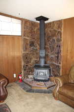 Interior details with carpet floors, a wood stove, and wood walls