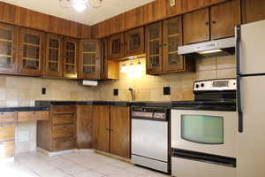 Kitchen with sink, white appliances, tasteful backsplash, and light tile patterned flooring