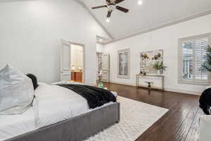 Bedroom with ensuite bath, ceiling fan, dark wood-type flooring, crown molding, and high vaulted ceiling