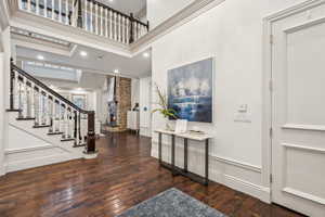 Foyer featuring a towering ceiling, crown molding, and dark wood-type flooring