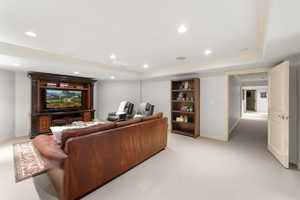 Carpeted living room with a tray ceiling and ornamental molding