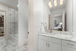 Full bathroom featuring toilet, vanity, combined bath / shower with glass door, and ornamental molding