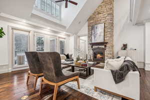 Living room with high vaulted ceiling, crown molding, dark hardwood / wood-style floors, ceiling fan, and a fireplace