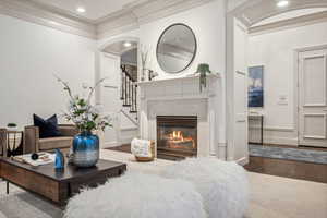 Living room featuring wood-type flooring, crown molding, and a tiled fireplace