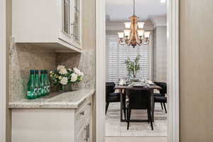 Dining room with ornamental molding and an inviting chandelier