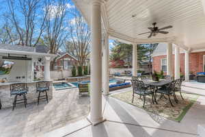 View of patio / terrace featuring a bar, ceiling fan, and a pool with hot tub