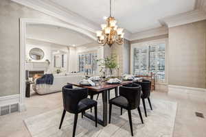 Carpeted dining space featuring crown molding and a chandelier