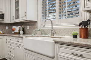 Kitchen with tasteful backsplash, sink, and white cabinets