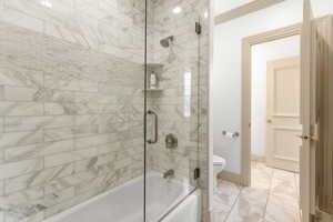 Bathroom featuring combined bath / shower with glass door and toilet