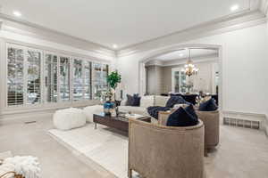 Carpeted living room with crown molding and an inviting chandelier