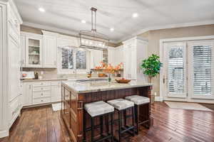 Kitchen featuring white cabinets, decorative light fixtures, a kitchen island, and dark hardwood / wood-style flooring