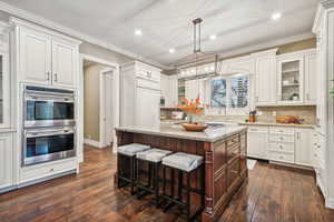 Kitchen featuring white cabinets, a center island, dark hardwood / wood-style flooring, and double oven