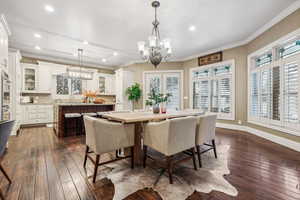 Dining space featuring sink, dark hardwood / wood-style flooring, a chandelier, and ornamental molding