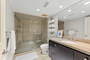 Bathroom featuring tile patterned floors, a shower with door, vanity, and toilet