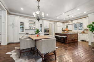 Dining space featuring dark hardwood / wood-style flooring, ornamental molding, and a notable chandelier