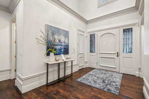 Entryway with dark hardwood / wood-style flooring and ornamental molding